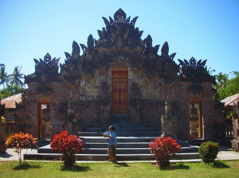 Balinese women carrying offering walking past an impressive Balinese temple in Buleleng Region North Bali. 