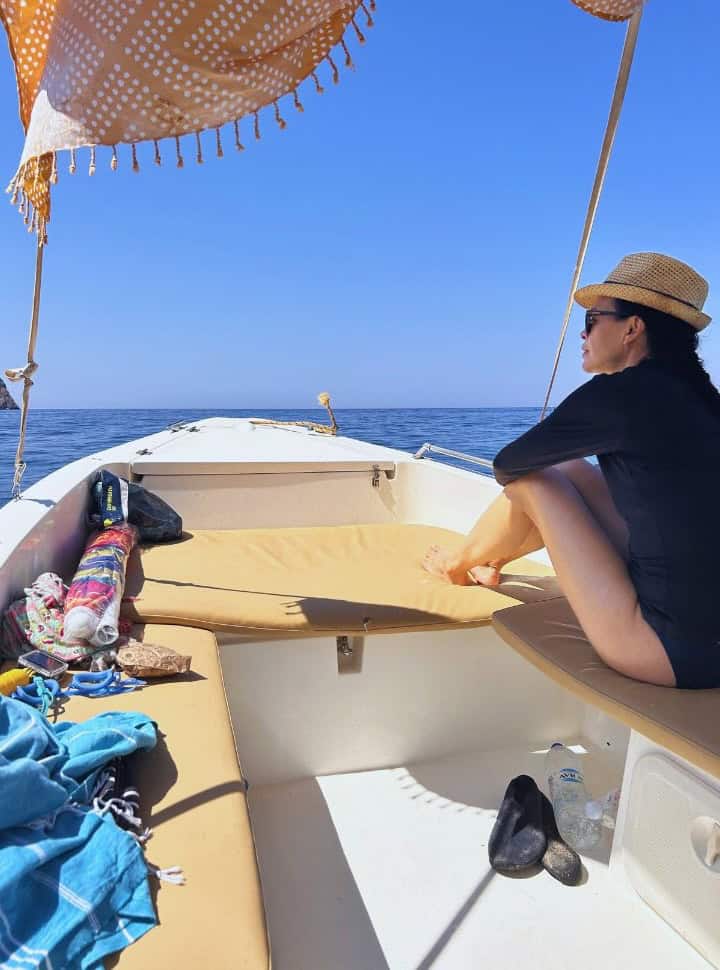 woman on a small boat gazing over the water just off shore at Corfu island Greece