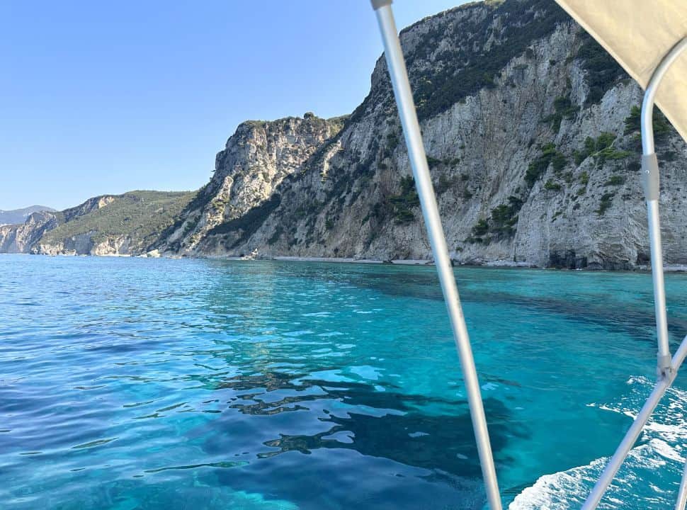 People rent a boat in Corfu without license and visit deserted small beaches with stunning blue water, along white cliffs