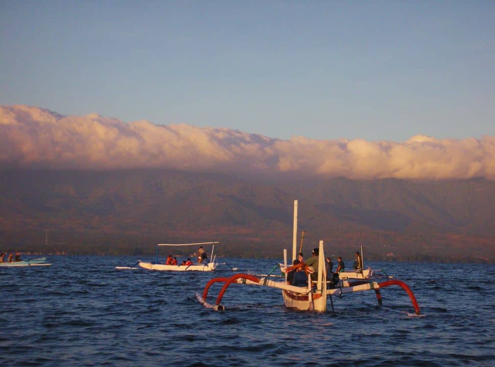 traditional boats from Lovina offering dolphin tours along the shore with in the background stunning mountains at sunrise