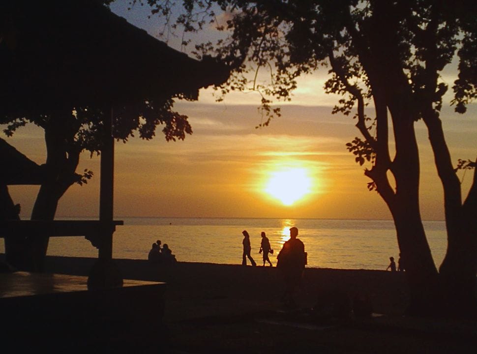 people walking along the beach of in Lovina by sunset