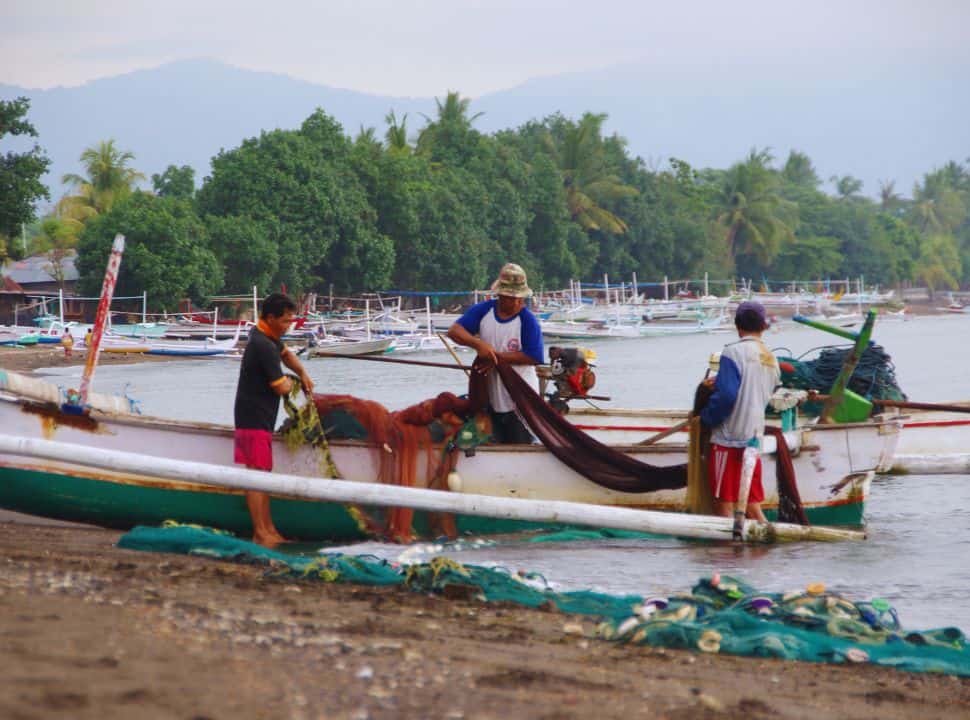 three fishermen arranging their nets at their boat located right at the beach in Lovina Bali