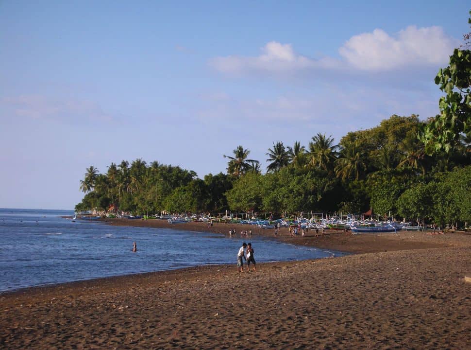 black sanded beach of Lovina, which a row of local fishing boats and a long strip of trees along the sand