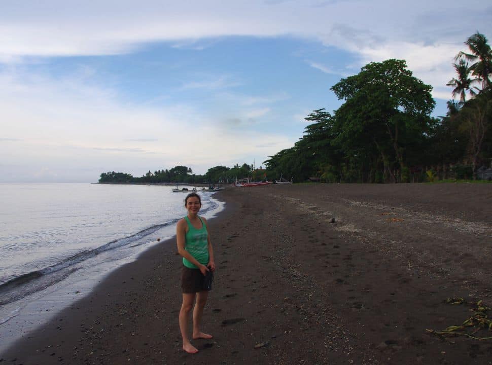 woman posing along the shore of a deserted lovina beach bali where the sand is volcanic black