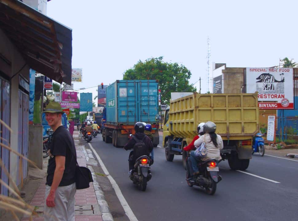 man standing along a main road full with trucks and motorbikes just off the town of Lovina north Bali