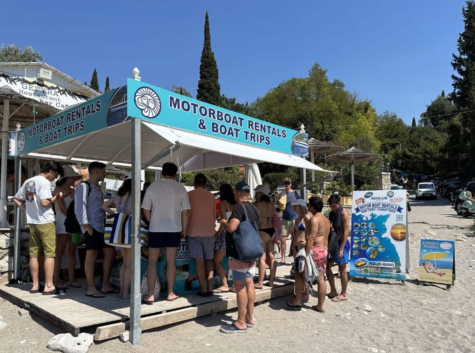 people queuing to rent a boat in corfu without license at Liapades beach nearby Paleokastritsa Corfu island
