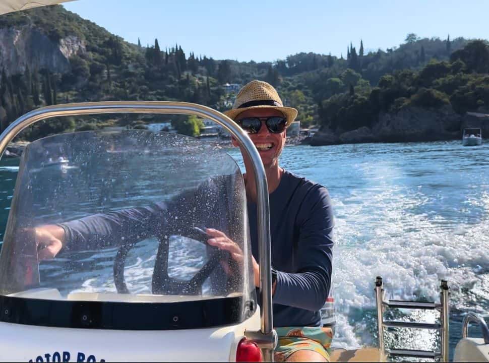 man driving a boat from Liapades Corfu off for a tour along the coast