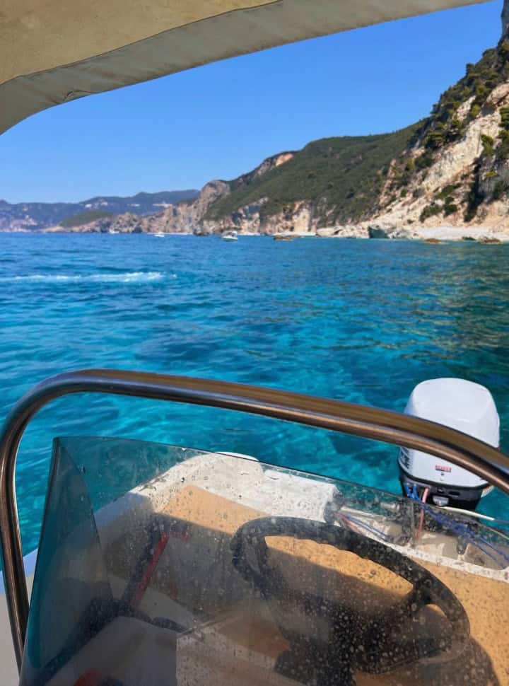 steering wheel of the small boat with its outboard engine at a crystel clear blue ocean in Corfu Greece