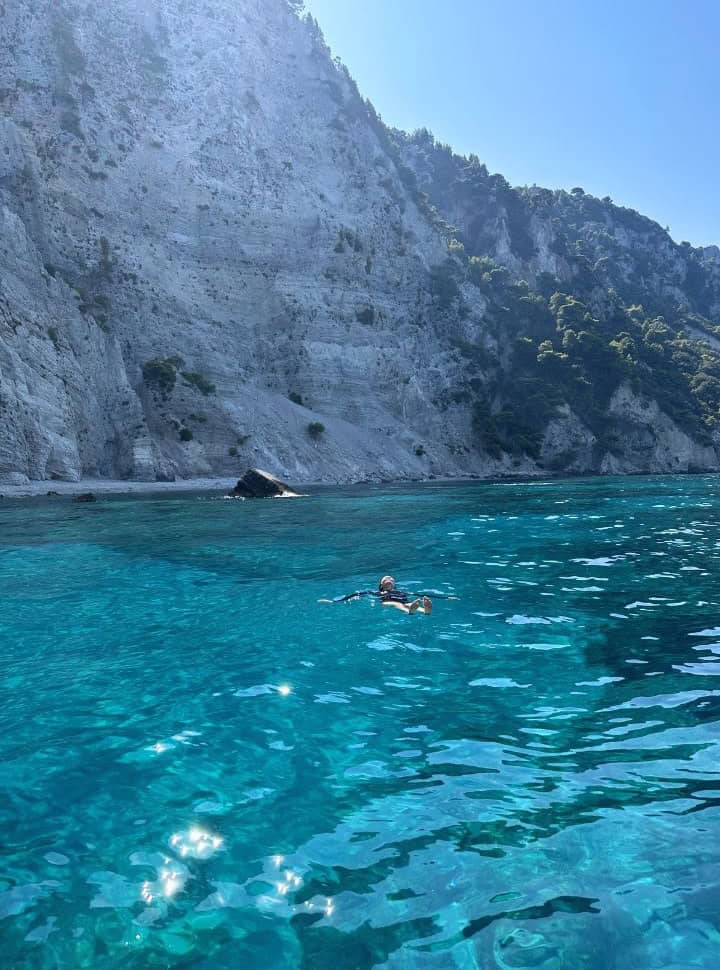 woman floating in the water enjoying the stunning blue water when renting a boat in Corfu without license.