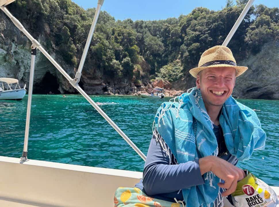 man sitting on a rental corfu boat eating a snack