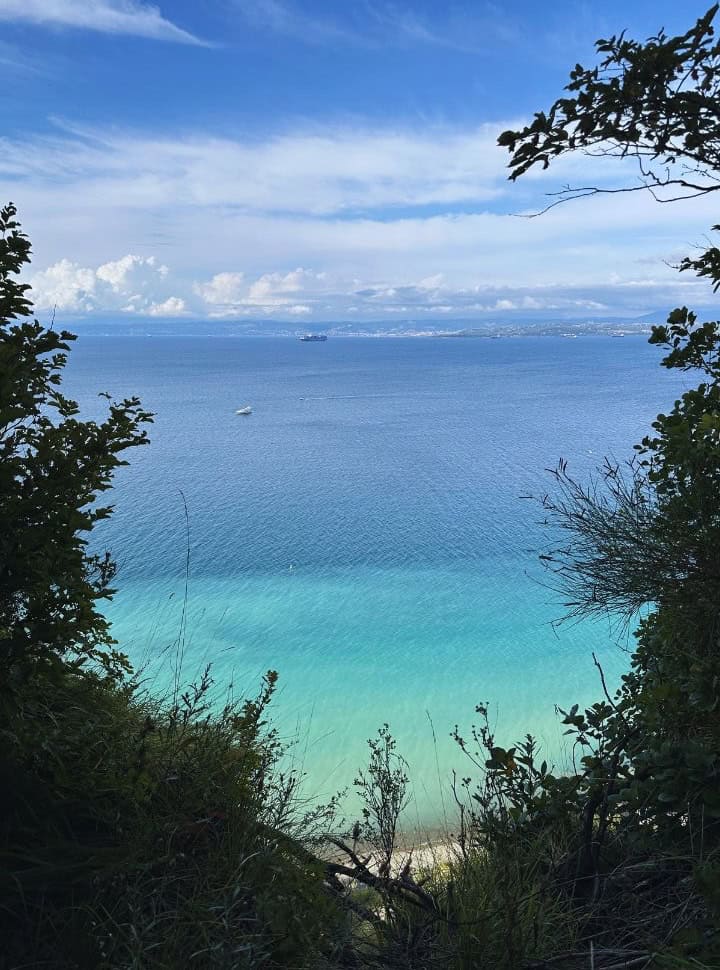 stunning view of a turquoise and blue water with boats near the coast of Slovenia, in the far distance Italy is visible