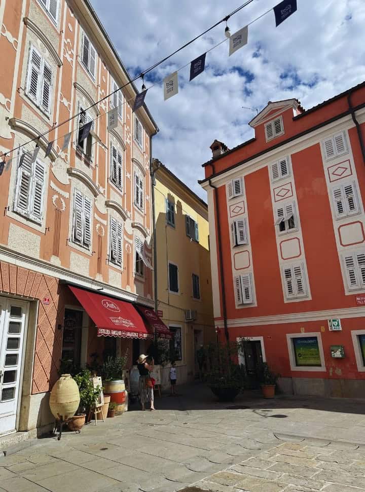 little square in Izola Slovenia with a beautiful building in the color red and brown with decorations