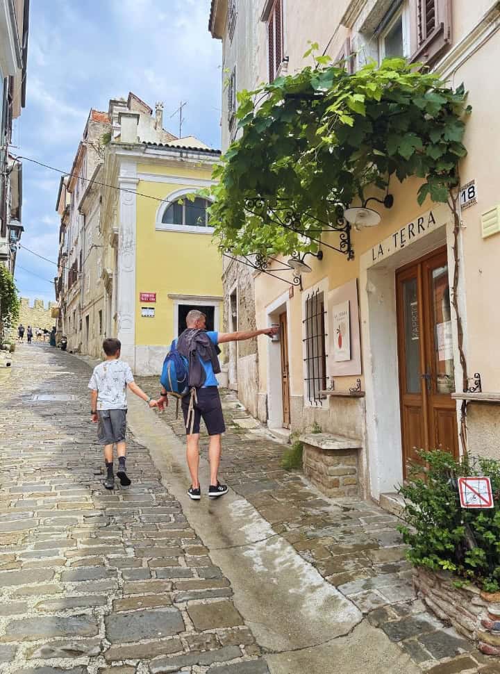 father and son walking along the cobbled streets of Piran looking at the colorful buildings