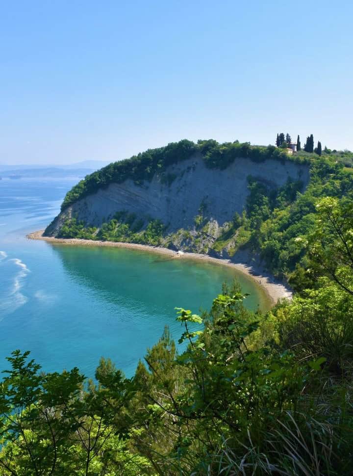 view on a quiet bay with stunning turquoise water set within the green cliffs along the coast Slovenia Adriatic ocean
