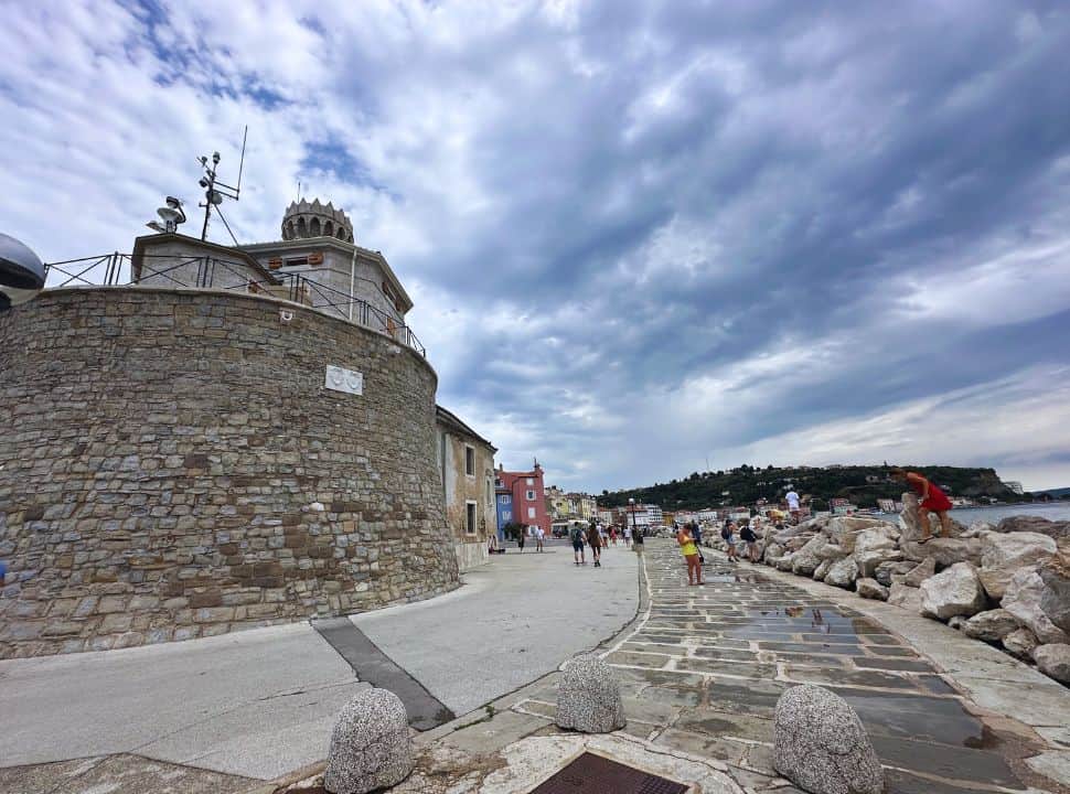 walkway along a high wall on one side and boulders and the ocean on the other side at Piran Slovenia