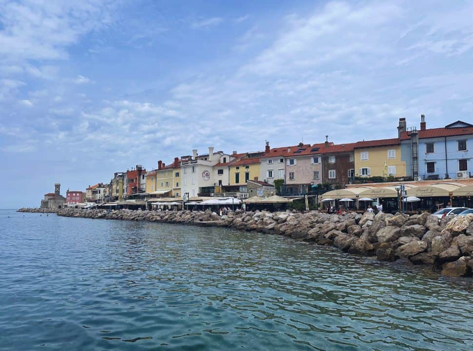 row of colorful houses with restaurants along the ocean at Piran Slovenia