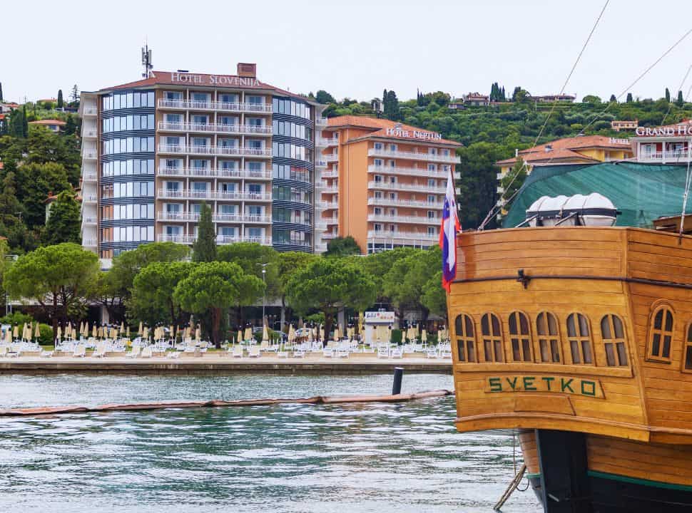 large hotel buildings at Portorož beach full with sunloungers, a large boat is docked in Slovenia coast.