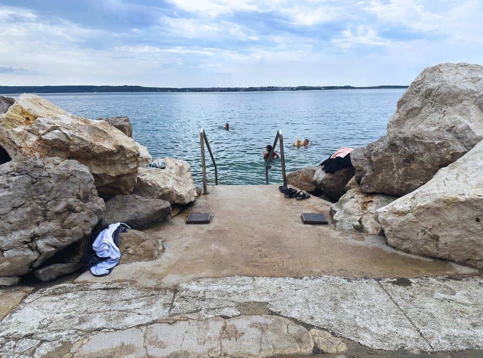 stairs set among large boulders where people can get in the ocean, Piran Slovenia beaches.