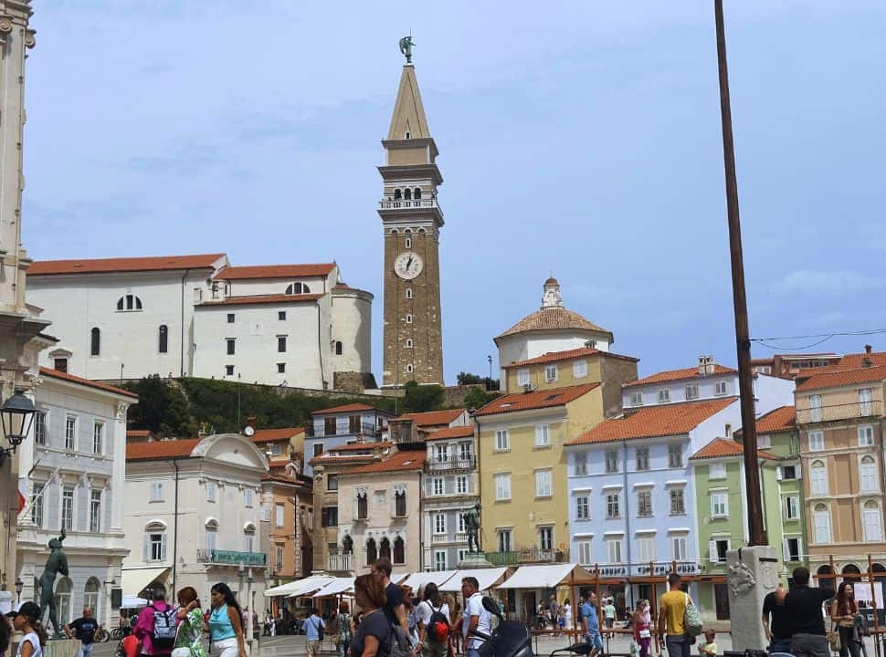 the main square of Piran with colorful buildings, the church is located in the back on the hill and is visible from the square