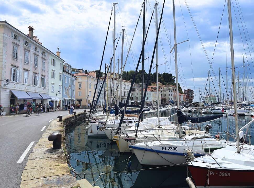 Piran waterfront harbor with small sailing boats and colorful houses lined up along the main street when entering the historical town. 