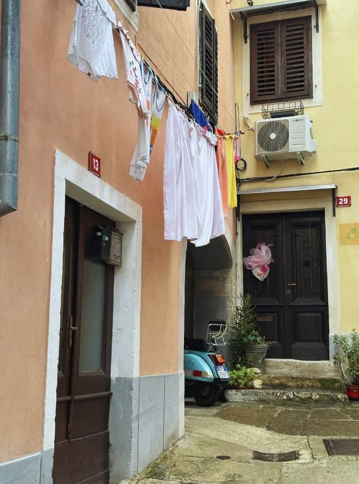 little colorful street with a vespa parked and cloths hung up to dry in Izola Slovenia
